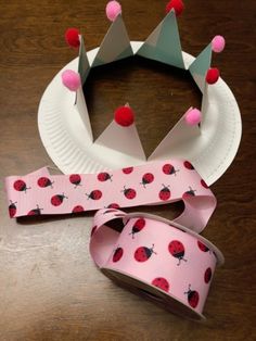 a paper plate with a crown and ribbon on it next to a roll of tape