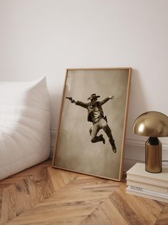 a photograph of a man jumping in the air with his arms outstretched on a wooden floor next to a lamp