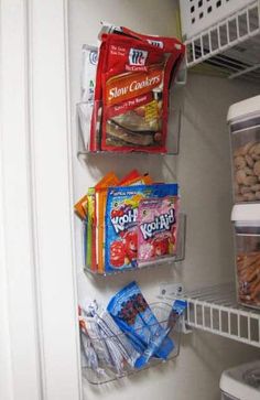 an open refrigerator door with food and snacks on the bottom shelf, including candy bars