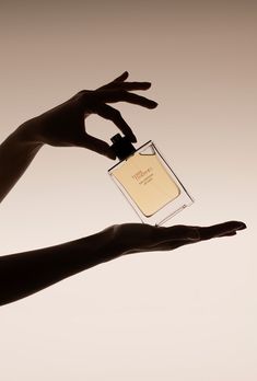 two hands holding an empty bottle of perfume