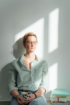 a woman sitting in front of a stack of books with her hands on her hips