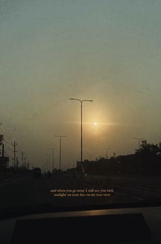 the sun is setting over an empty street with no cars or people on it, as seen from inside a vehicle