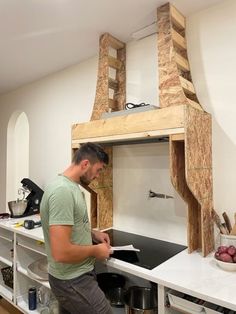 a man standing in front of a kitchen sink under a wooden structure that has been built into the wall