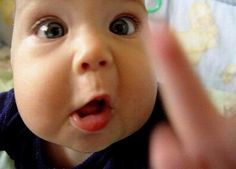 a close up of a baby making a face with his hand and fingers in front of him