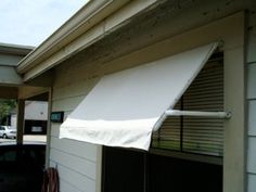 an awning on the side of a building with cars parked in the driveway behind it