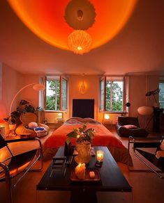 a living room filled with lots of furniture next to tall windows covered in bright orange lights