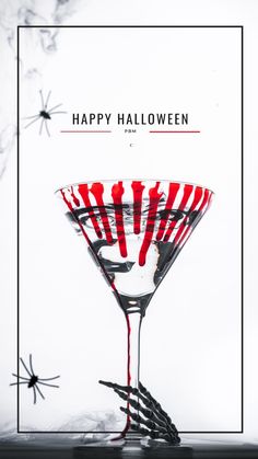 a martini glass with red liquid and sprinkles on the rim that says happy halloween