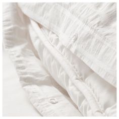 an unmade bed with white linens and buttons on the bottom half of it