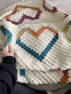 a person is laying on a bed with a crocheted blanket that has been made to look like a heart