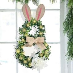 a wreath with bunny ears and flowers hanging from the front of a window sill