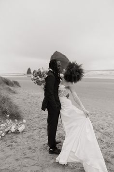 a bride and groom kissing on the beach