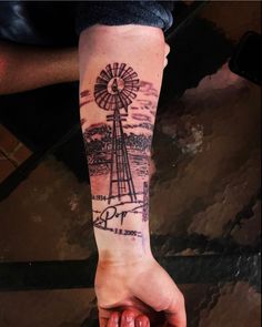 a person holding their hand with a windmill tattoo on it