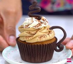 a cupcake with chocolate frosting and sprinkles sitting on a plate