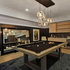 a pool table in the middle of a room with lights hanging from it's ceiling