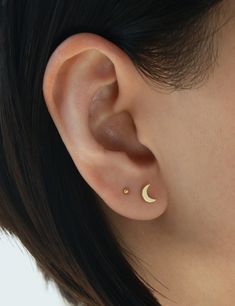 a woman's ear is shown with the moon and star piercings on it