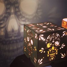 a lit up box with a skull on it next to a candle holder and wallpaper