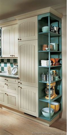 a kitchen with green cabinets and white cupboards in the corner, filled with dishes