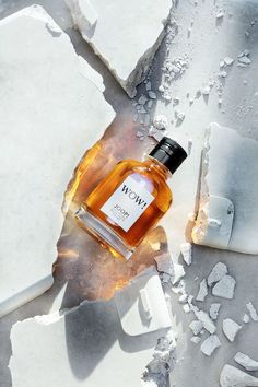 a bottle of whiskey sitting on top of broken pieces of glass next to an ice block