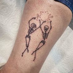 a tattoo on the leg of a person with two skeletons and stars in their hands