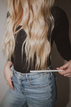 a woman with long blonde hair is holding a toothbrush