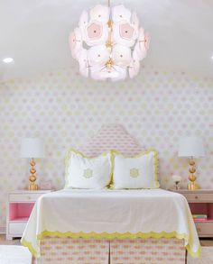 a pink and yellow bedroom with polka dot wallpaper, white bedding and two nightstands