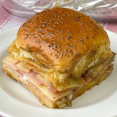 a ham and cheese sandwich on a white plate with a pink table cloth behind it