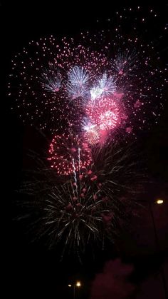 fireworks are lit up in the night sky with pink and blue lights on it's side