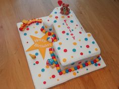 a birthday cake for a one year old boy on a wooden table with a teddy bear