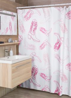 a pink and white shower curtain with cowboy boots on it next to a bathroom sink