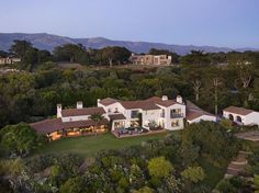 an aerial view of a house with trees and mountains in the background