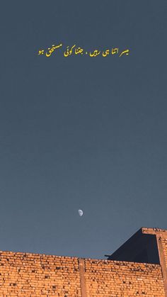 an airplane flying over a brick building with the moon in the sky and writing on it