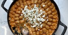 a skillet filled with tater tots covered in cottage cheese