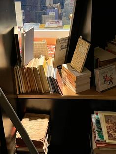 many books are sitting on a shelf next to a window