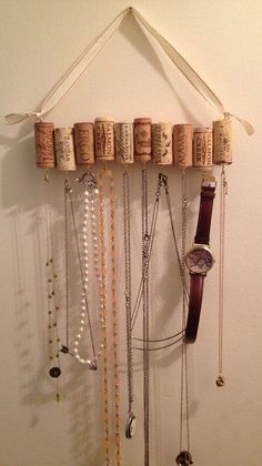 wine corks are hanging on the wall with necklaces and watches attached to it