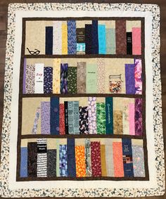 a quilted wall hanging on the side of a wooden floor with many different colored fabrics