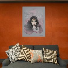 a couch with many pillows on it in front of an orange wall and a painting