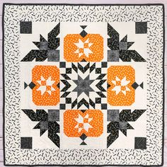 a black and white quilt with orange flowers on the center is featured in this image