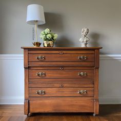 a wooden dresser sitting in front of a lamp on top of a hard wood floor