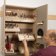 a man is looking at many small items in a cabinet that he has built into the wall