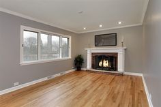 an empty living room with wood floors and a fireplace