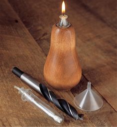 a small wooden candle holder next to some metal items on a wood table with a lit candle in the middle