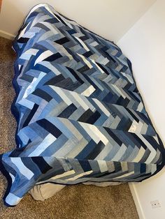 a bed with a blue and white comforter on it's side next to a wall