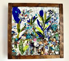 a wooden frame filled with lots of different types of glass and pebbles on top of a white wall