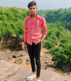 a young man standing on top of a rock