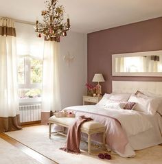 a bedroom with a large bed and chandelier hanging from it's ceiling