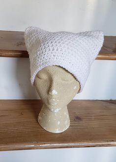 a white knitted hat sitting on top of a wooden shelf