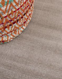 an orange and white hat sitting on top of a floor next to a brown rug