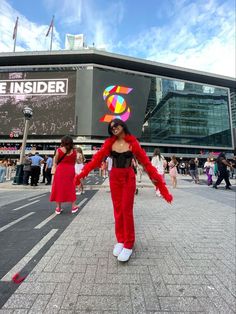 a woman dressed in red dancing on the street