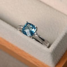 an engagement ring with a blue topazte surrounded by white diamonds in a box