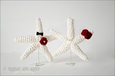 two white crocheted starfishs with red flowers on them, one has a black bow tie